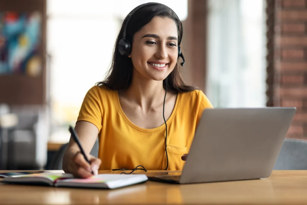 Mujer joven con diademas tomando nota de Cursos y Clases de idiomas para empresas